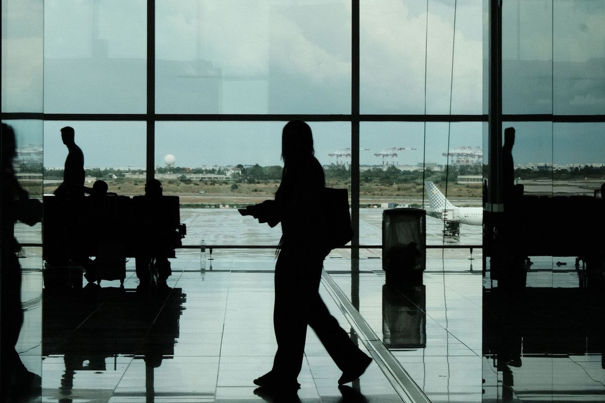 A traveller in Barcelona El Prat terminal with a Vueling jet beyond the glass