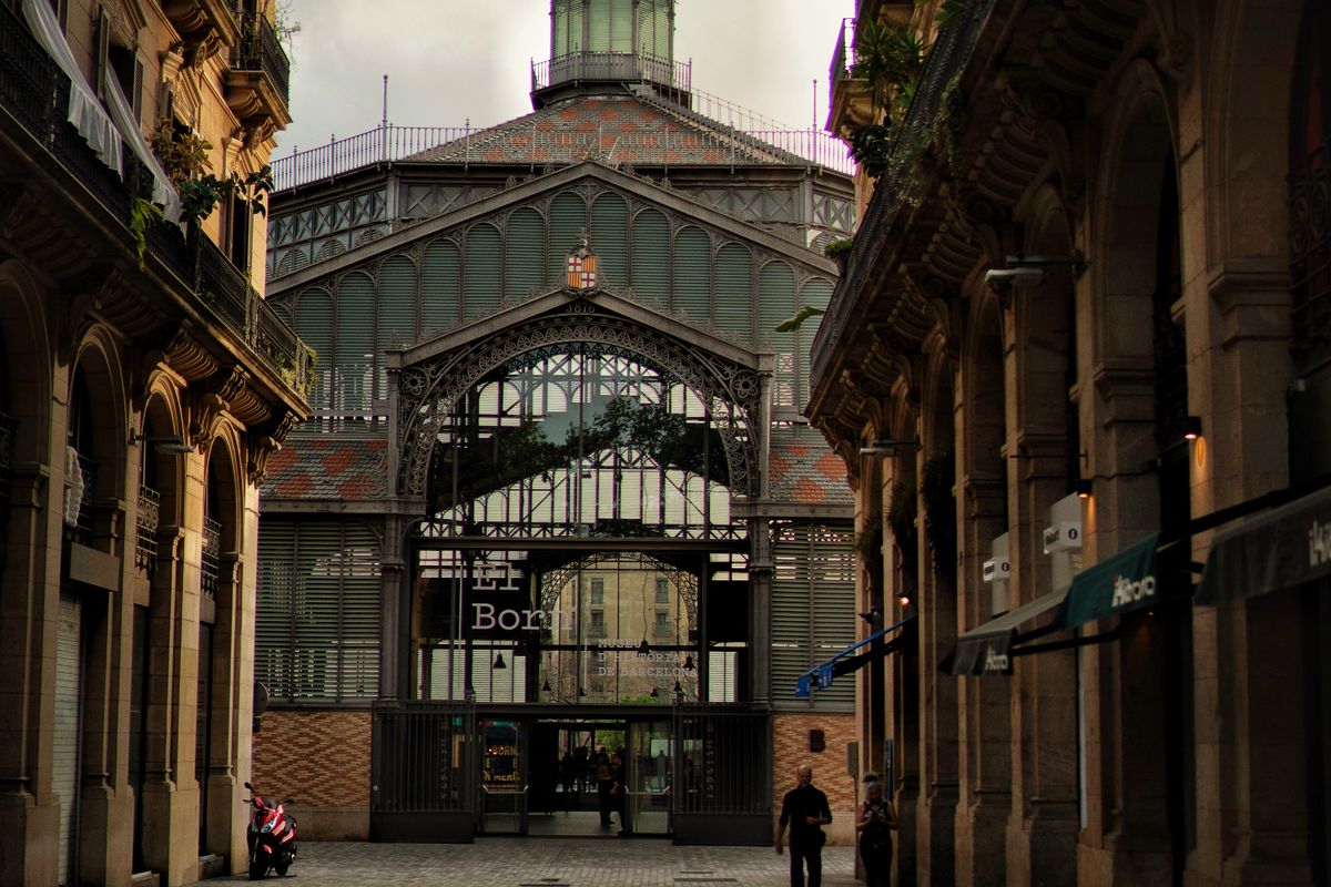 Cobbled El Born lane framing the iron-and-glass El Born CCM market hall